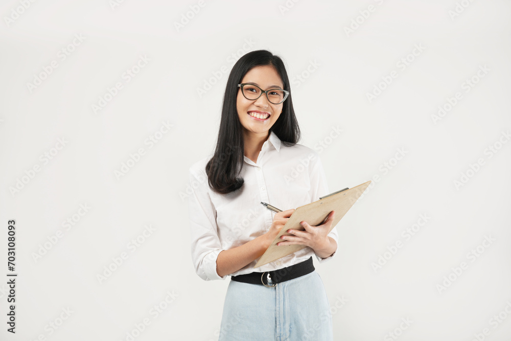 An Asian woman smiles warmly while writing on a clipboard, exuding confidence and positivity in a professional setting. An Asian woman smiles warmly while writing on a clipboard, exuding confidence and positivity in a professional setting.