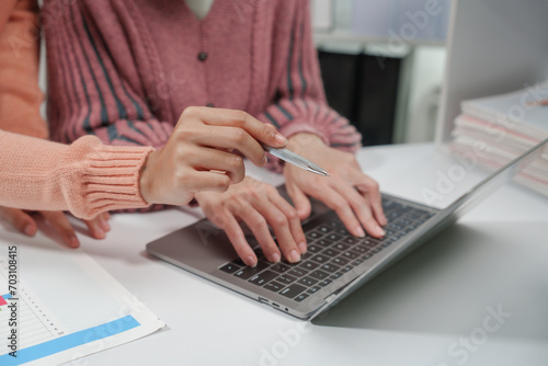 two individuals are engaged in accounting work. One person is wearing a pink sweater, and they both are reviewing financial charts and graphs, likely for a small business.