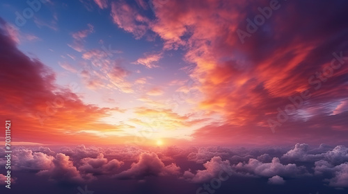 Field covered in greenery with a bare tree under a cloudy sky during the pink sunset