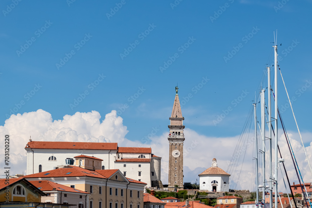 Fishing and sailing boats in serene harbor of coastal town Piran, Slovenia, Europe. Tranquil Venetian port in Adriatic Mediterranean sea. Summer at Slovenian coastline. Scenic view of cathedral