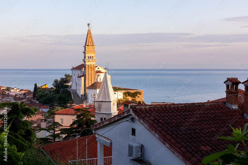 Panoramic aerial view at sunrise of coastal town Piran, Primorska, Slovenia, Europe. Shimmering azure waters of Adriatic Sea. Soft morning light touching timeless beauty of Mediterranean architecture