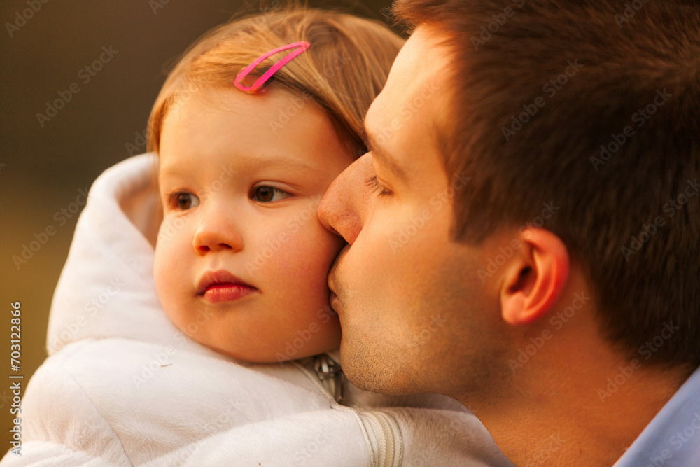 Father's affectionate kiss, daughter's thoughtful demeanor Father's affectionate kiss, daughter's thoughtful demeanor