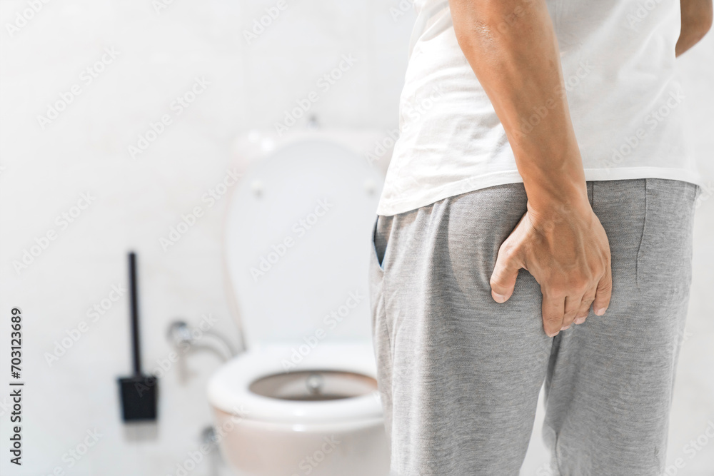 Man suffering from hemorrhoid in rest room, man has diarrhea holding his butt in toilet, diarrhea constipation. Men have diarrhea and are looking for shit. - obrazy, fototapety, plakaty 