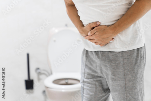Men have stomachache and use their hands to hold their stomach In the bathroom. Constipation or colon cancer. diarrhea and severely toxic food. Man touch belly in the bathroom. Abdominal pain photo