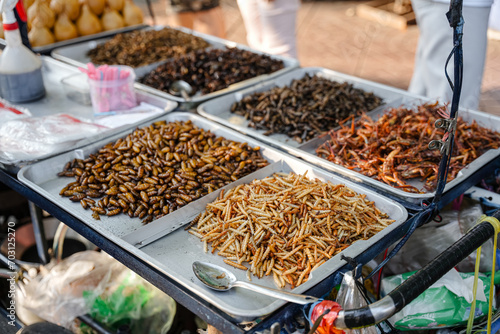 Fried insects (locust, worm, cricket, pupa, and giant waterbug) as street food on a vendor stall, Thailand. © michaelnero