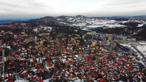 Aerial view of red roofs on buildings in town in snow covered mountains