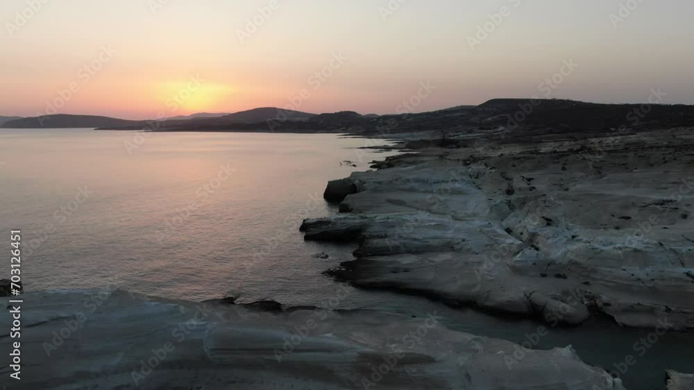 Drone view in Greece flying over a moon shaped white rock area in Milos island at sunrise next to the dark blue sea Drone view in Greece flying over a moon shaped white rock area in Milos island at sunrise next to the dark blue sea