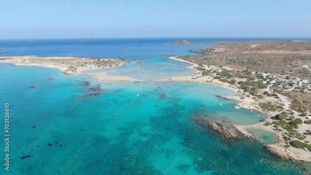 Drone view in Greece flying over Elafonisi white sand narrow beach, clear blue water on the sides and brown landscape on a sunny day Drone view in Greece flying over Elafonisi white sand narrow beach, clear blue water on the sides and brown landscape on a sunny day