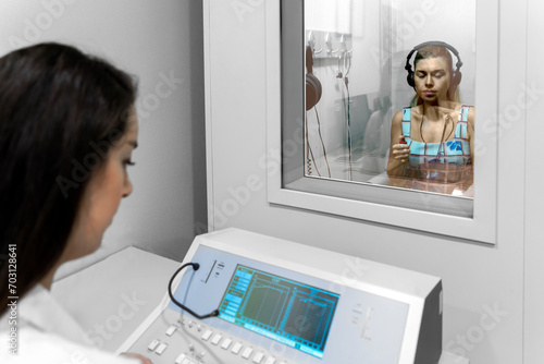 Audiologist woman doing the hearing exam to a mixed race woman patient using an audiometer in a special audio room. photo
