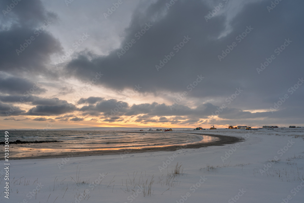 Dramatic sky over horizon and village by the ocean on a winter afternoon. Skallelv, Northern Norway