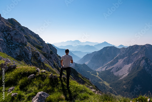 Hiker man with scenic view of mountain peak Grintovec, majestic Kamnik-Savinja Alps, Slovenia, Europe. Magnificent hiking trail in untamed Karawanks, Austrian border. Magical mountains Slovenian Alps photo