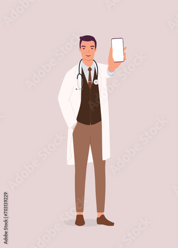 One Smiling Male Doctor In Lab Coat And Stethoscope Standing And Showing His Cellphone With Blank Empty Screen. Full Length.