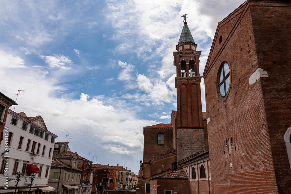 Close up view of bell tower of Church of Saint James Apostle nestled in charming town of Chioggia, Venetian Lagoon, Veneto, Italy. Sightseeing in historic old town of Chioggia. Walking along canals