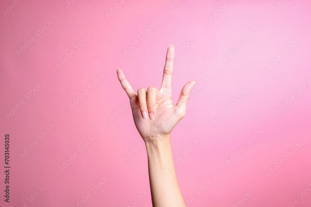 Hand showing rock sign with fingers gesture against pink background, human hand gesture - obrazy, fototapety, plakaty 