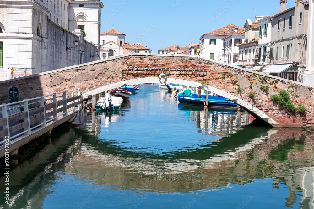 Breathtaking beauty of historical bridge Ponte Foscarini in town of Chioggia in the picturesque Venetian Lagoon, Italy. Calm atmosphere as the stunning water reflections grace the charming canal Vena