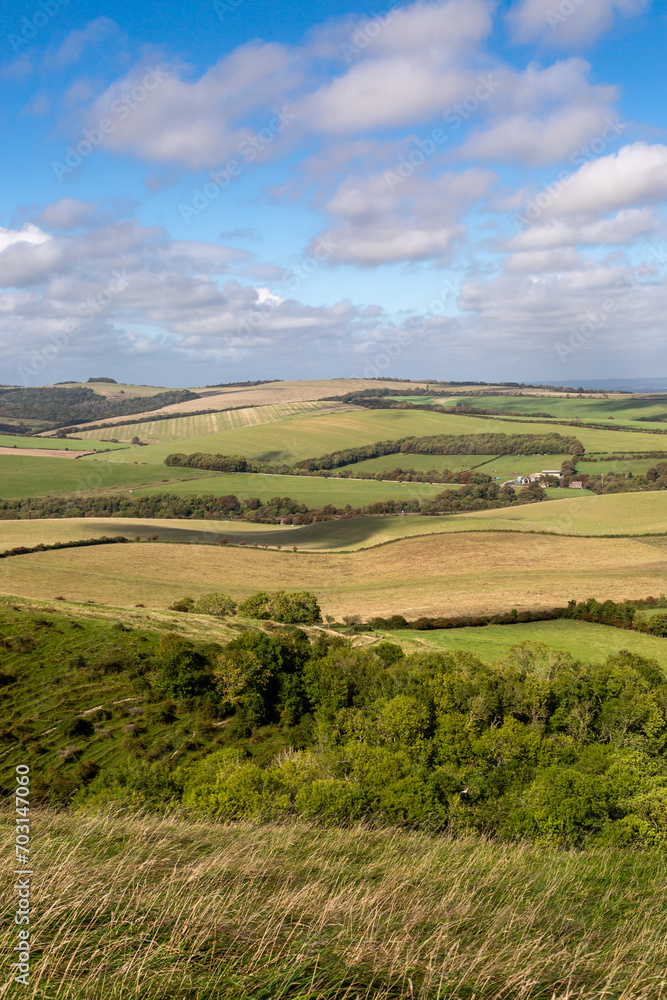 Looking out over hills and fields in rural Sussex, with a blue sky overhead Looking out over hills and fields in rural Sussex, with a blue sky overhead