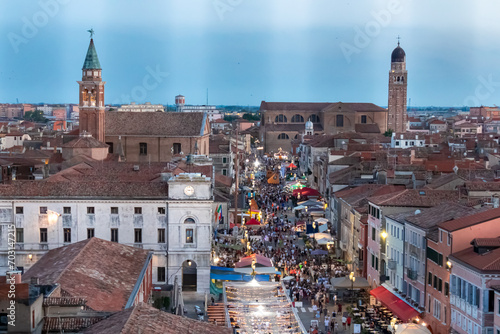 Aerial view of pedestrian street Corso del Popolo in tourist town Chioggia, Venetian Lagoon, Veneto, Italy. Viewing point from clock tower at sunset overlooking Venetian architecture and landmarks