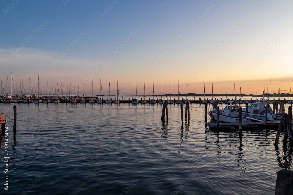 Beautiful sailing boats in picturesque port of charming town of Chioggia at sunrise, nestled in the stunning Venetian Lagoon of the Veneto region in Italy. Tranquil atmosphere in summer
