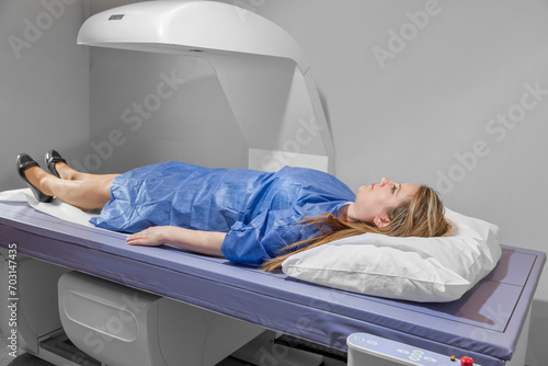 Female patient undergoing x-ray scan research for osteoporosis, bone densitometry examining woman in C Bone Densitometer Machine. checking the density of bone tissue
