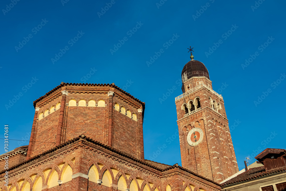 Sunrise view of bell tower of Cathedral Santa Maria Assunta in charming town of Chioggia, Venetian Lagoon, Veneto, Italy. Sightseeing in historic old town. First sun beams on landmark and blue sky