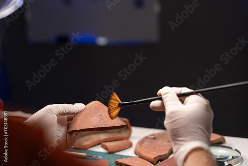 Archeologist clean old pottery dish working late night in office