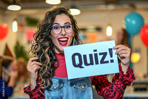 Quiz concept image with happy woman holding a board sign with written word Quiz inside an open space office at work