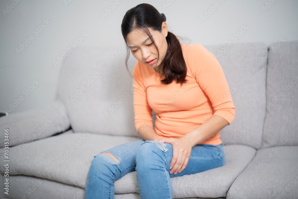 Young Asian beautiful woman leg while sitting on sofa at home, physical pain and therapist concept. Young Asian beautiful woman leg while sitting on sofa at home, physical pain and therapist concept.