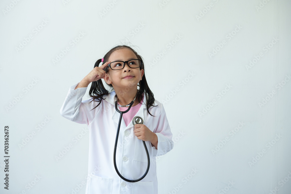 Smiling girl wearing glasses wearing a doctor's coat in medical practice Using a stethoscope, the doctor stands and thinks. Treatment plan on white background. Career concept. Plan for the future. Smiling girl wearing glasses wearing a doctor's coat in medical practice Using a stethoscope, the doctor stands and thinks. Treatment plan on white background. Career concept. Plan for the future.