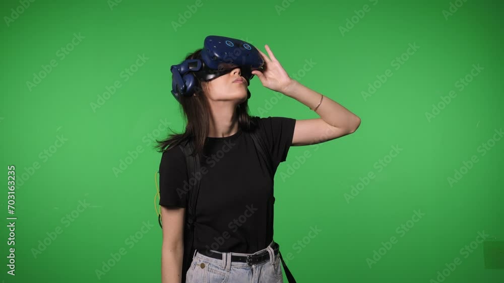 Portrait of a young woman in virtual reality glasses with a joystick on a green screen background. The concept of the metaverse. Chromakey. Portrait of a young woman in virtual reality glasses with a joystick on a green screen background. The concept of the metaverse. Chromakey.