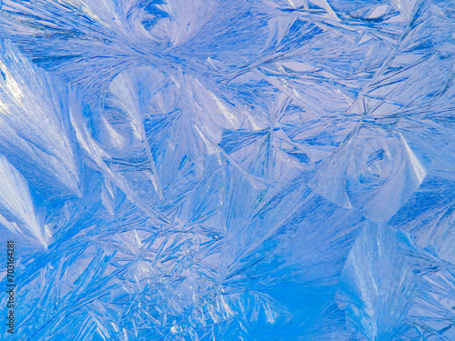 Beautiful ice pattern and sunlight close up on window glass early in the morning, natural winter background 