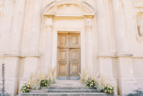 Bouquets of flowers stand on the steps of an ancient church