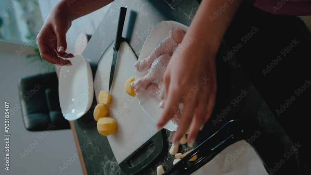 Hands holding a raw chicken drumstick over a plate, preparation for cooking with more chicken and potatoes in the background, ideal for a cooking tutorial or recipe guide video. Hands holding a raw chicken drumstick over a plate, preparation for cooking with more chicken and potatoes in the background, ideal for a cooking tutorial or recipe guide video.