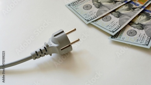 Electrical plug with cable and dollar bills on a white background. Electricity bill saving concept. The concept of attracting money energy.