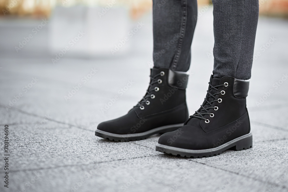 A pair of dark brown leather boots and grey denim jeans make a stylish statement in this urban fashion photo.