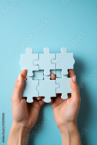 Light blue puzzle pieces in Caucasian hands on blue background,