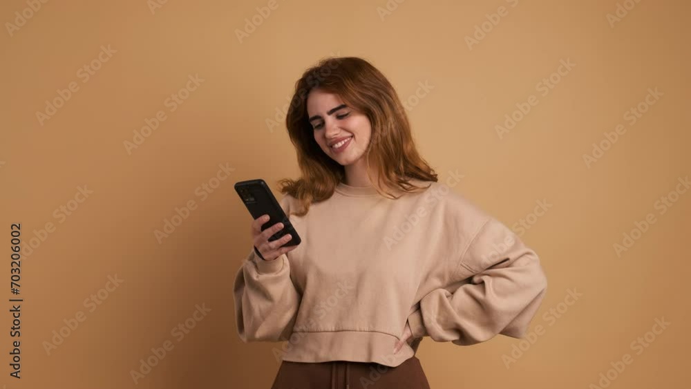 Smiling young woman using phone and looking proud at camera Smiling young woman using phone and looking proud at camera