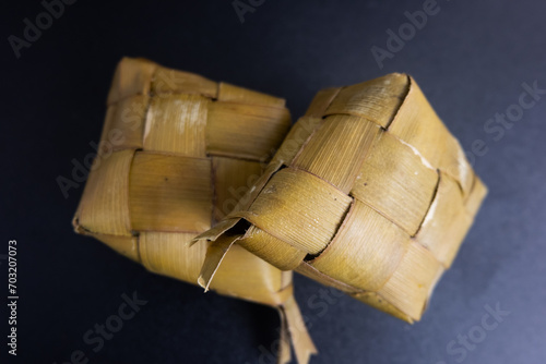 Ketupat still wrapped in coconut leaves isolated on a black background