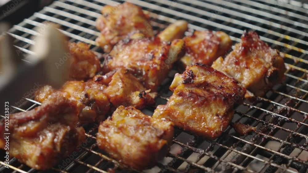 Close up shot of a grill with pork ribs roasting, cook's hand working with tongs Close up shot of a grill with pork ribs roasting, cook's hand working with tongs
