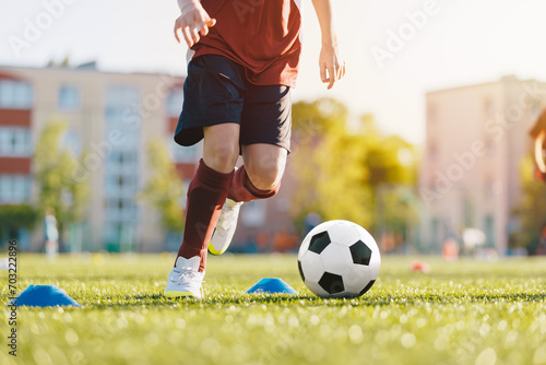 Soccer player on field with ball. Close up of boy kicking soccer ball. Slalom drill during a football training session
