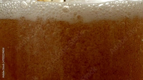 Pouring beer into glass. Closeup slow motion shot. Bubbles rising up stream of a