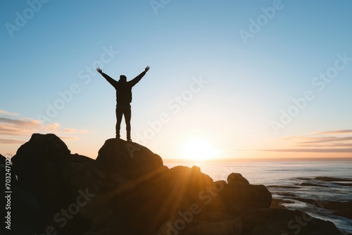 Homme au sommet d'une montagne levant les bras. Man on top of a mountain raising his arms.