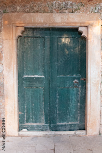 old wooden door in a wall leading into old building © Filip
