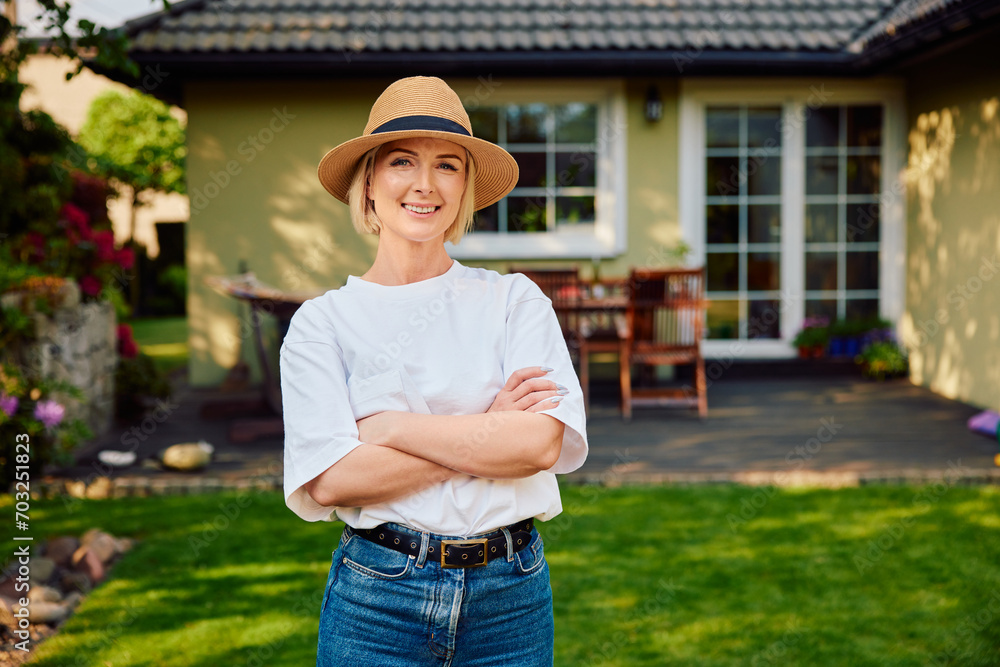 Portrait of smiling woman standing in backyard outside of her house
