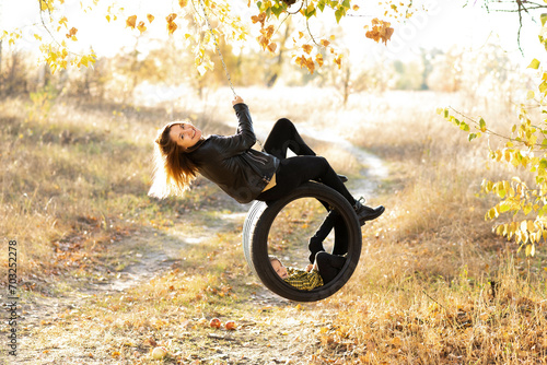 Joyful young mother having fun with her little son in nature, sitting together on a swing wheel suspended from a tree photo