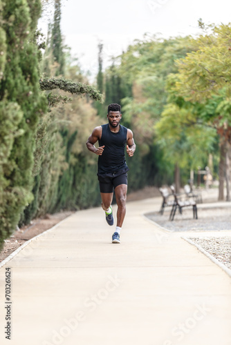 African American sportsman in activewear jogging along park during morning exercise