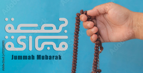 Jummah Mubarak blessed happy Friday Arabic Modern calligraphy, Selective focus image hand of Muslim woman holding prayer beads. photo