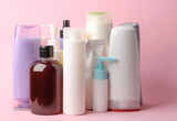 Many different shampoo and other cosmetic product bottles on pink background