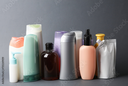 Different shampoo and other cosmetic product bottles on dark gray background photo