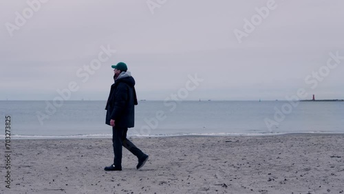 Young male in coat standing  and looking at the horizon with during the bright sunset. Concept of solitude to non tourist spots places.