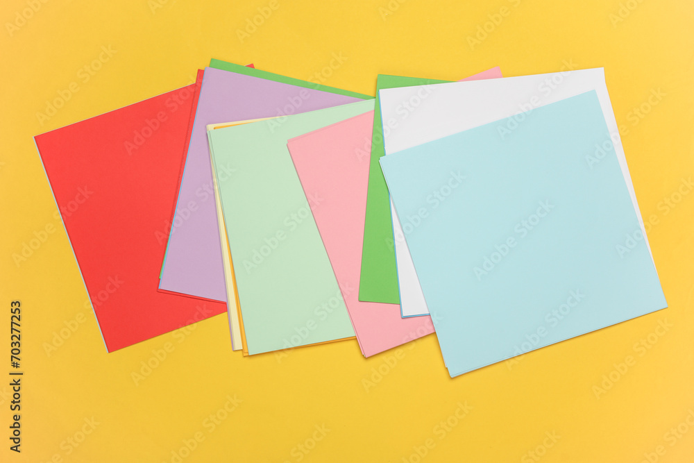 Square sheets of paper for origami creativity on yellow background Square sheets of paper for origami creativity on yellow background